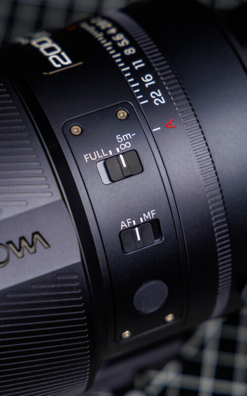 Close-up of a camera lens showing focus range and autofocus/manual focus switches, with detailed markings and textured surfaces visible on the lens body.