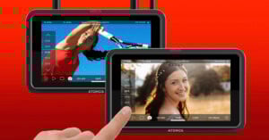 Two Atomos Ninja camera monitors display different scenes; one shows a woman playing tennis, the other a woman smiling outdoors. A hand touches the screen of the front monitor. The background is a red gradient.