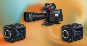 Three professional video cameras are displayed against a colorful, abstract background: a large shoulder-mounted camera in the center and two compact cube-style cameras with digital screens on either side.