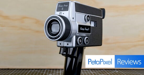 A vintage Canon Snap 8 video camera is displayed on a stand against a light wooden background, with the Petapixel Reviews logo overlaid in the bottom right corner.