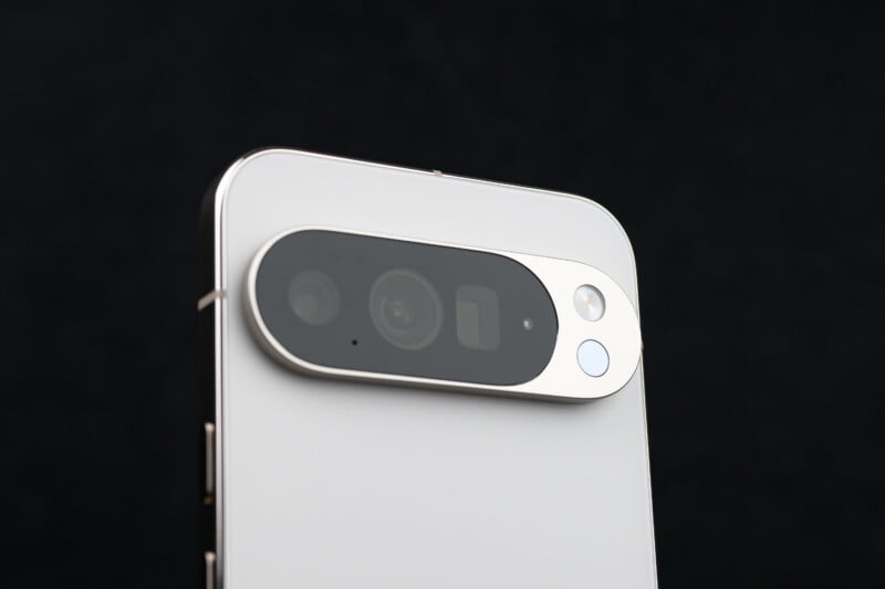 Close-up of the rear camera module on a modern smartphone with a silver frame and white back, showing multiple lenses and a flash against a black background.