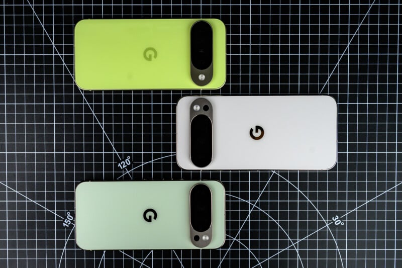 Three Google Pixel smartphones in pastel colors (green, white, and mint) are displayed on a black grid-patterned surface, each showing the back with the camera bar and Google "G" logo visible.