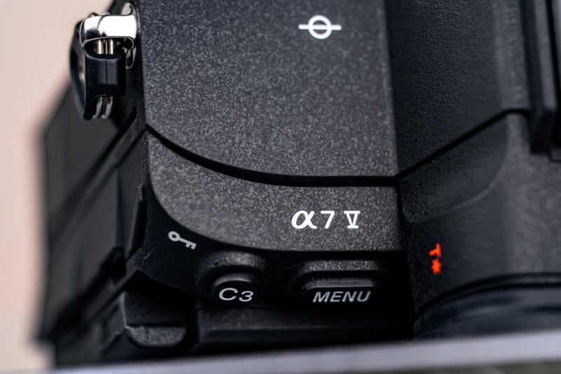 Close-up of a Sony Alpha 7 IV camera body, showing textured black surface, model name “α7 IV,” and buttons labeled “C3” and “MENU.”.