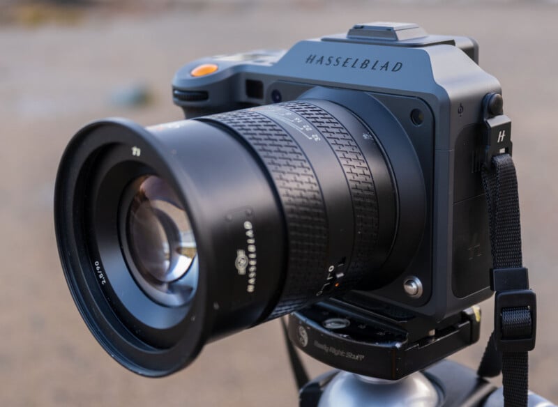 Close-up of a Hasselblad camera with a large lens mounted on a tripod, photographed outdoors with a blurred background.