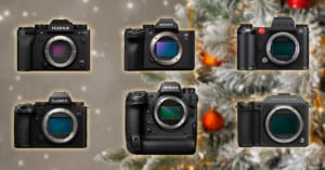Six different mirrorless camera bodies from Fujifilm, Sony, Leica, Panasonic Lumix, Nikon, and Hasselblad are arranged in front of a blurred, festively decorated Christmas tree.