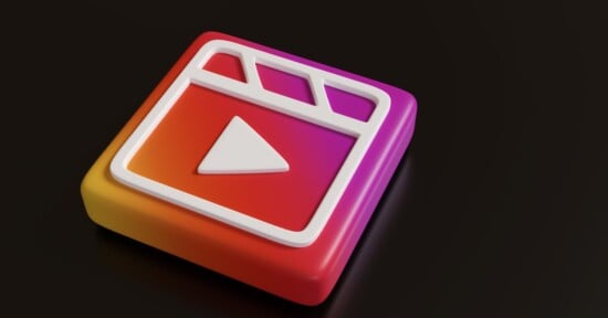 A 3D icon resembling a video play button and a clapperboard, set against a gradient backdrop of pink, orange, and purple. The icon has a square base with rounded edges, giving a modern and dynamic look.
