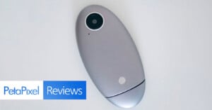 A silver, oval-shaped camera device with a lens at one end is placed on a white surface. In the bottom left corner, there is a "PetaPixel Reviews" logo.