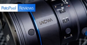 Close-up of a Laowa camera lens with focus and mode switches, featuring a "PetaPixel Reviews" banner in the top left corner.