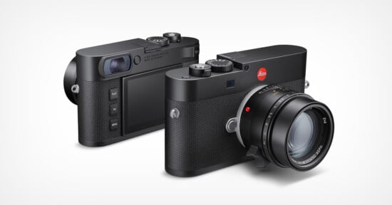 Two black Leica digital cameras are shown, one facing forward displaying the lens and the other turned to show the back with its screen and control buttons. Both cameras have a textured grip and classic, minimalist design.