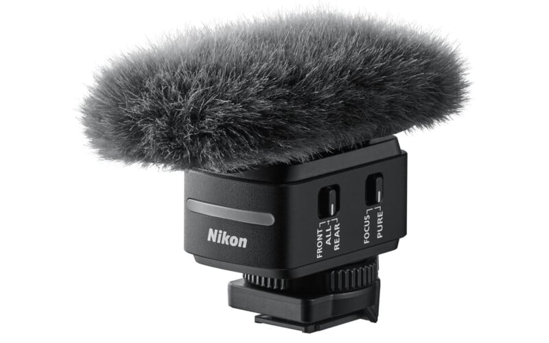 A Nikon microphone with a fluffy, grey windscreen sits atop a black mounting base, featuring labeled switches for audio settings.