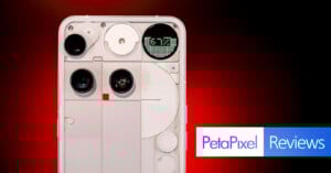 A white smartphone with exposed components and a unique rear design is displayed against a red-black gradient background. The screen shows "5:17." The Petapixel Reviews logo appears in the bottom right corner.