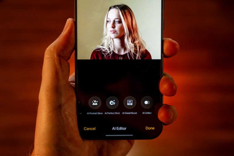 A hand holds a smartphone displaying a photo editing app with a portrait of a woman on screen. Editing options like AI Portrait Glow and AI Detail Boost appear below the image.