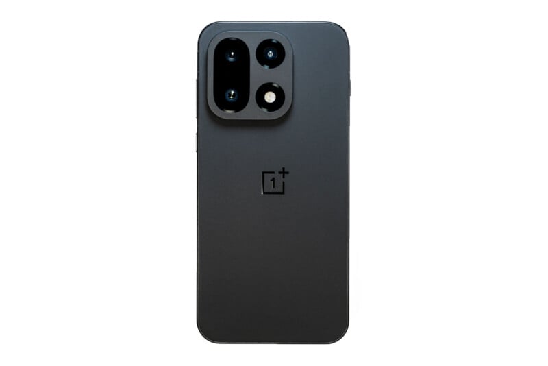 A black OnePlus smartphone is shown from the back, displaying the OnePlus logo and a large rectangular camera module with three lenses and a flash on a white background.