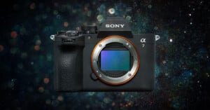 A Sony Alpha 7 mirrorless camera with no lens attached, showing the full-frame sensor, against a dark, bokeh-filled background.