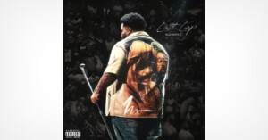 A man stands on stage holding a microphone, wearing a shirt with a large image of a person's face on the back. The background shows a crowd in grayscale. Text reads "Nostalgia Rod Wave.