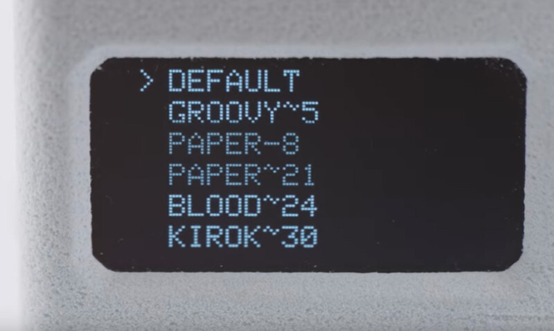A digital screen displays a menu with options: DEFAULT, GROOVY^5, PAPER~8, PAPER^21, BLOOD^24, and KIROK^30, with DEFAULT highlighted by a right arrow.