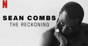 Black-and-white promotional image for “Sean Combs: The Reckoning” on Netflix, featuring Sean Combs looking directly at the camera with his hand resting on his face, wearing a ring.