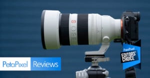 A large white Sony G Master telephoto lens mounted on a camera and tripod, with “PetaPixel Reviews” and “Editors’ Choice” banners overlaid in the corner against a blue background.