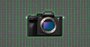 A Sony Alpha mirrorless camera with no lens attached is centered on a background of green binary code on a dark screen, resembling the digital rain from the Matrix.