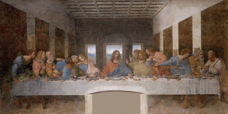 Painting of Jesus and his disciples sitting at a long table, sharing a meal. Jesus is at the center, with groups of disciples reacting emotionally around him. The background shows windows and an open doorway.