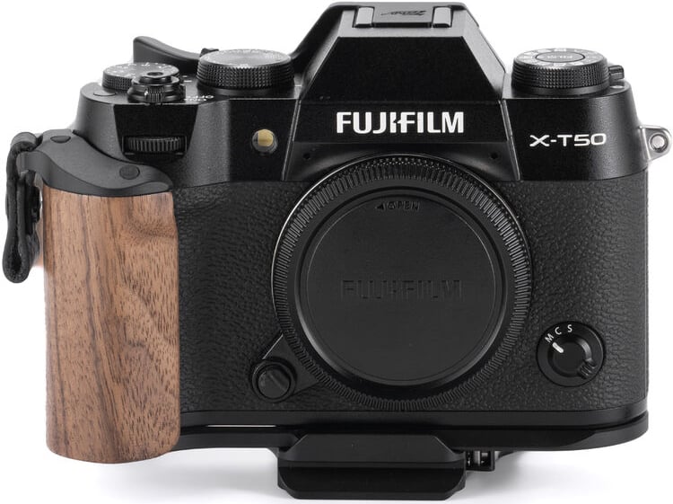A black Fujifilm X-T50 mirrorless camera with a body cap attached and a wooden grip on the left side, viewed from the front against a white background.