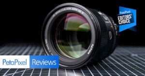A close-up of a camera lens on a grid-patterned surface, with "PetaPixel Reviews" and "Editors' Choice" text and badges overlaid.